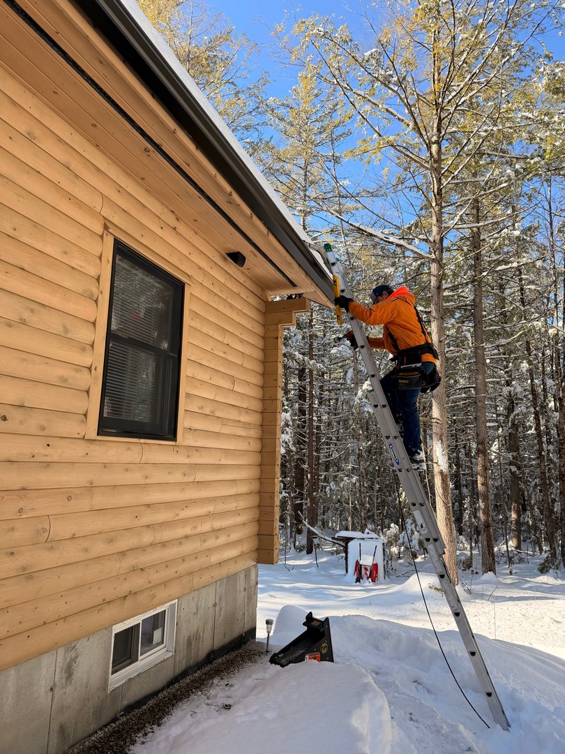 Crown Hill crew member in orange jacket installing heat tape in winter